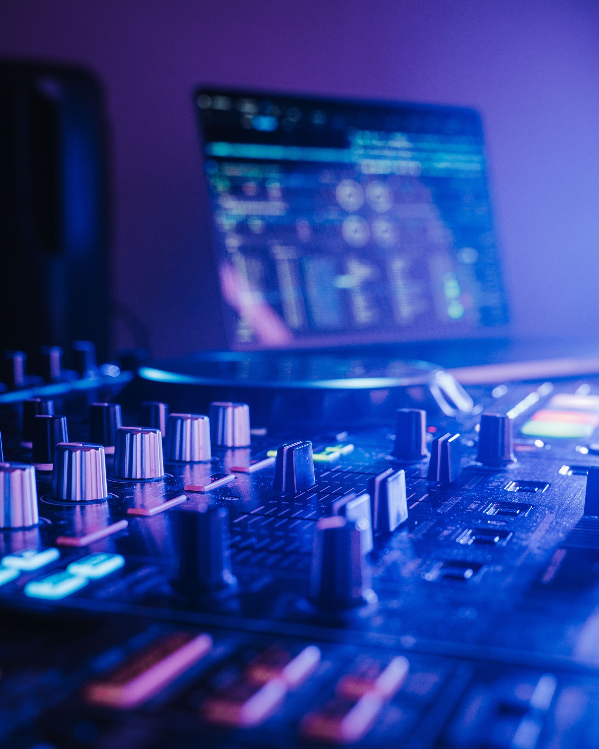 Professional audio mixing board connected to a laptop, displaying the various knobs and buttons.